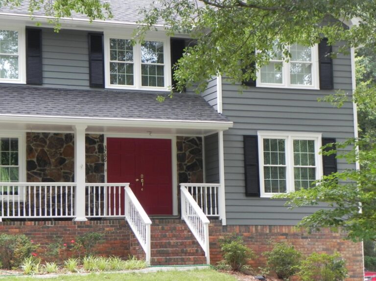 House exterior featuring double-hung vinyl windows, red front door, and stone accents, showcasing a modern design with low-maintenance features.