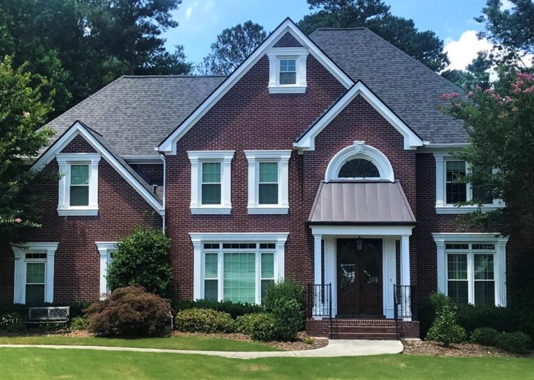 Elegant brick home featuring double-hung vinyl windows from the 700 Series, surrounded by lush greenery and a well-maintained lawn, showcasing energy-efficient design and classic architectural style.