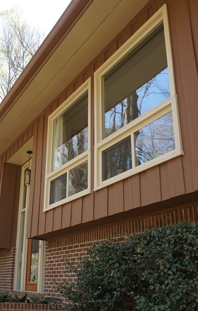 Double-hung vinyl windows in a residential setting, showcasing energy-efficient glass and low-maintenance design, complementing the brown exterior of the home.