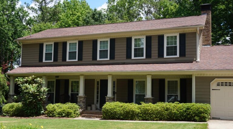 Modern two-story home featuring 700 Series double-hung vinyl windows with black shutters, surrounded by greenery and a well-maintained lawn, emphasizing energy efficiency and quality craftsmanship.