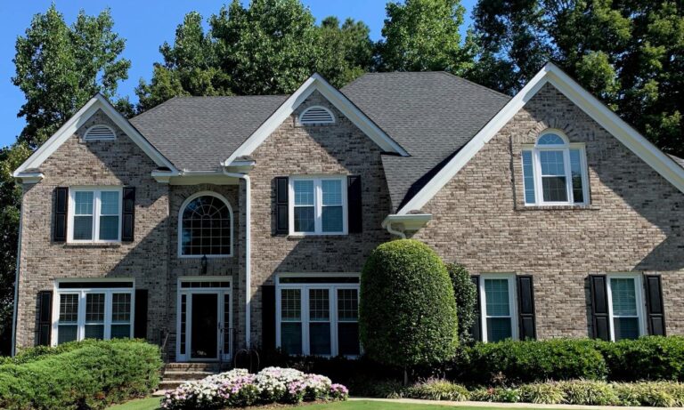 Elegant brick home featuring 700 Series double-hung vinyl windows, manicured landscaping, and a welcoming entrance, highlighting energy efficiency and quality craftsmanship.