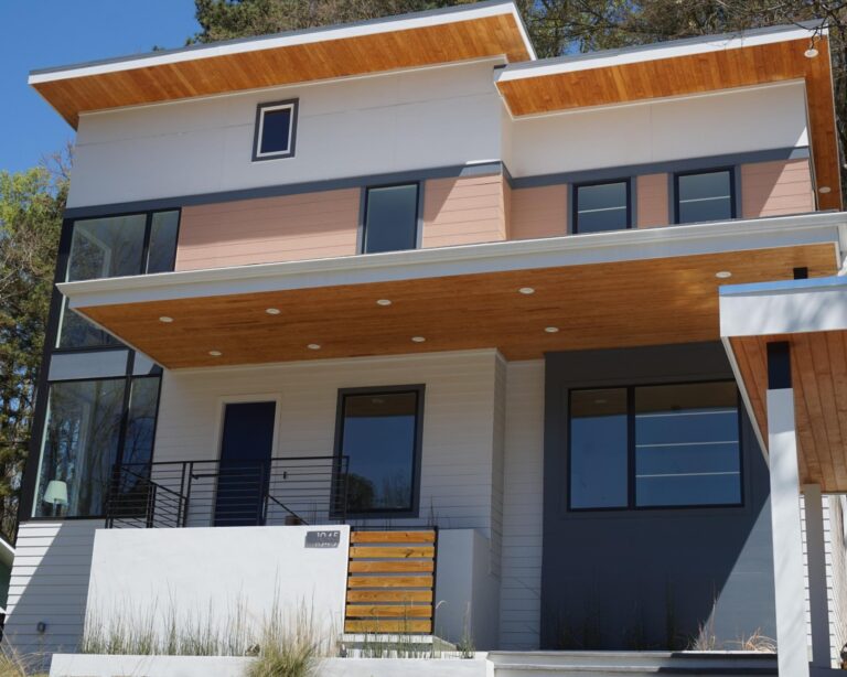 Modern two-story house with large windows, wooden overhang, and a contemporary design, showcasing custom architectural elements and inviting entrance.