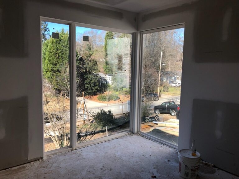 Floor-to-ceiling fixed vinyl windows showcasing outdoor view, part of the 900 series by Windowcrafters, emphasizing energy efficiency and custom-built design.