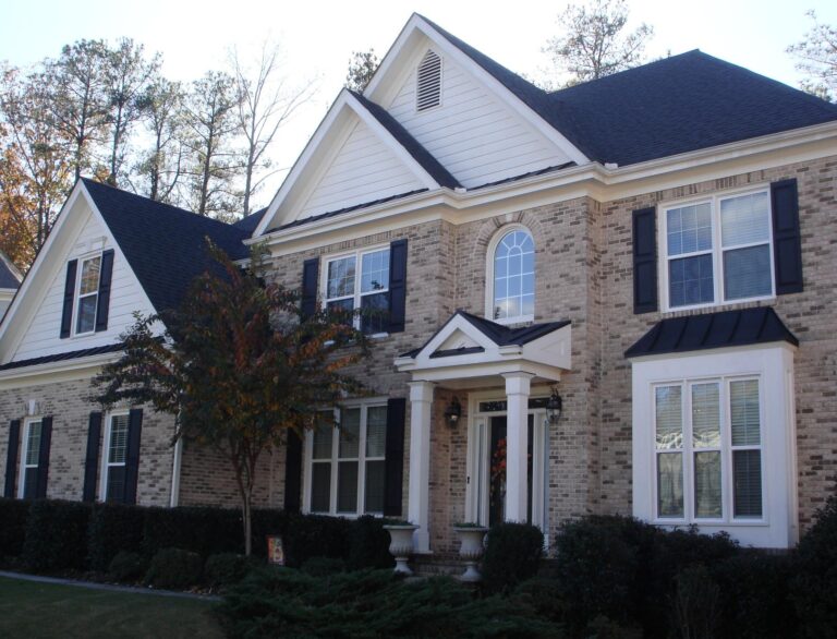 Elegant two-story brick home featuring single-hung vinyl windows, black shutters, and a welcoming front porch, highlighting custom-built energy-efficient window options from Windowcrafters.