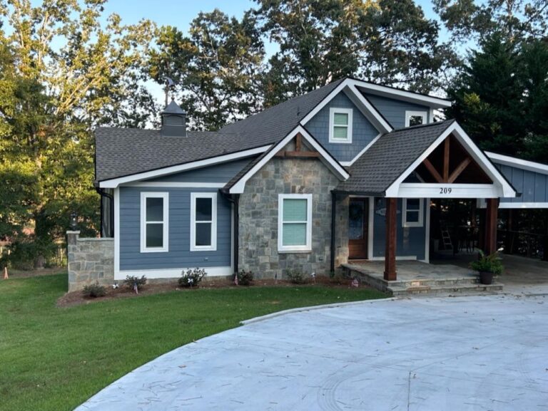 Modern home exterior featuring a combination of stone and blue vinyl siding, showcasing energy-efficient windows and a welcoming porch with a wooden overhang.