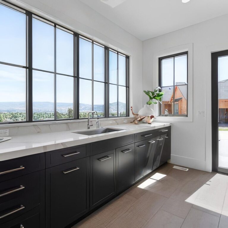 Modern kitchen featuring custom vinyl windows, sleek black cabinetry, and a view of the outdoors, highlighting the quality and design options available from Windowcrafters.