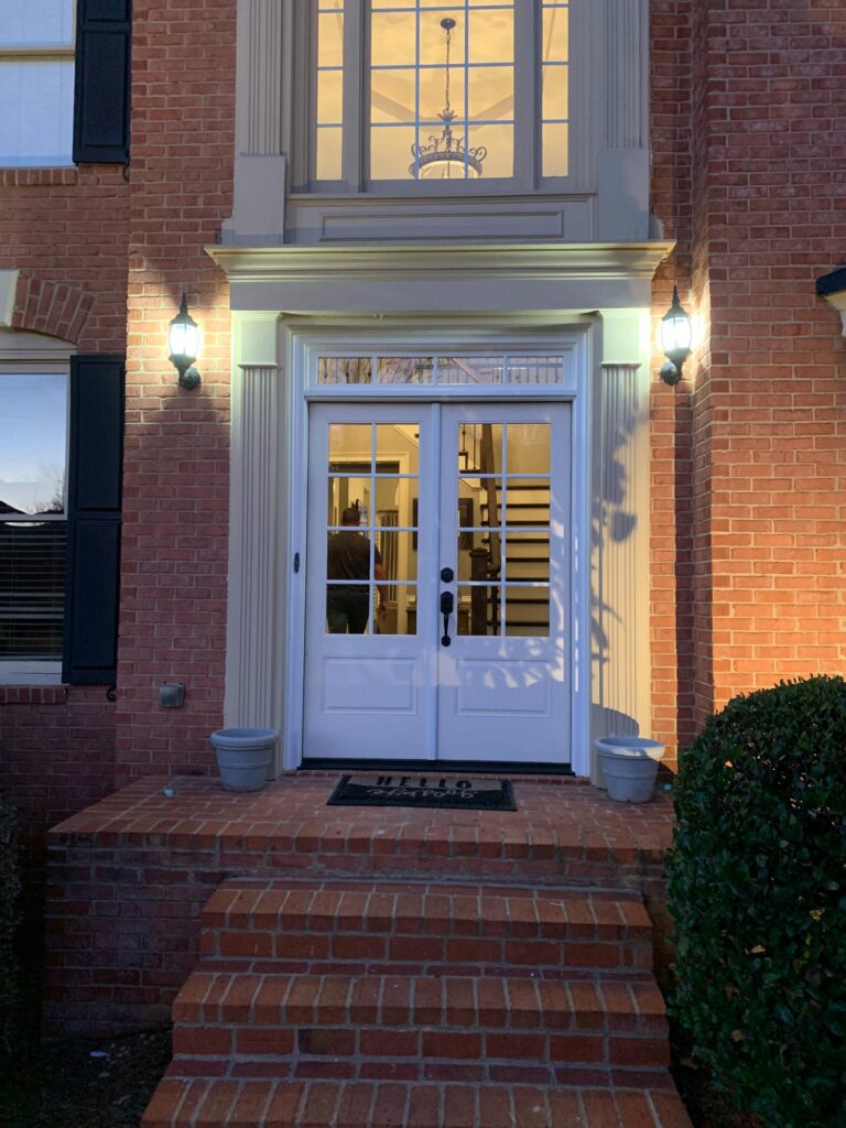 Double front doors with decorative glass panels, brick exterior, and outdoor lighting, showcasing an inviting entrance for homeowners in Atlanta.