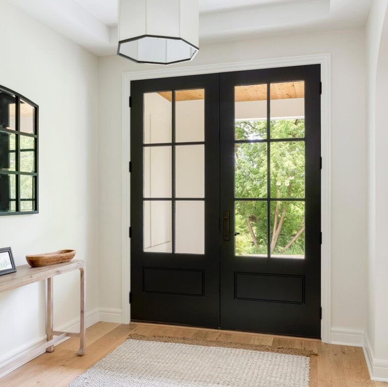 Black double entry doors with glass panels in a modern interior, showcasing natural light and a welcoming entryway, emphasizing quality and design in exterior doors.