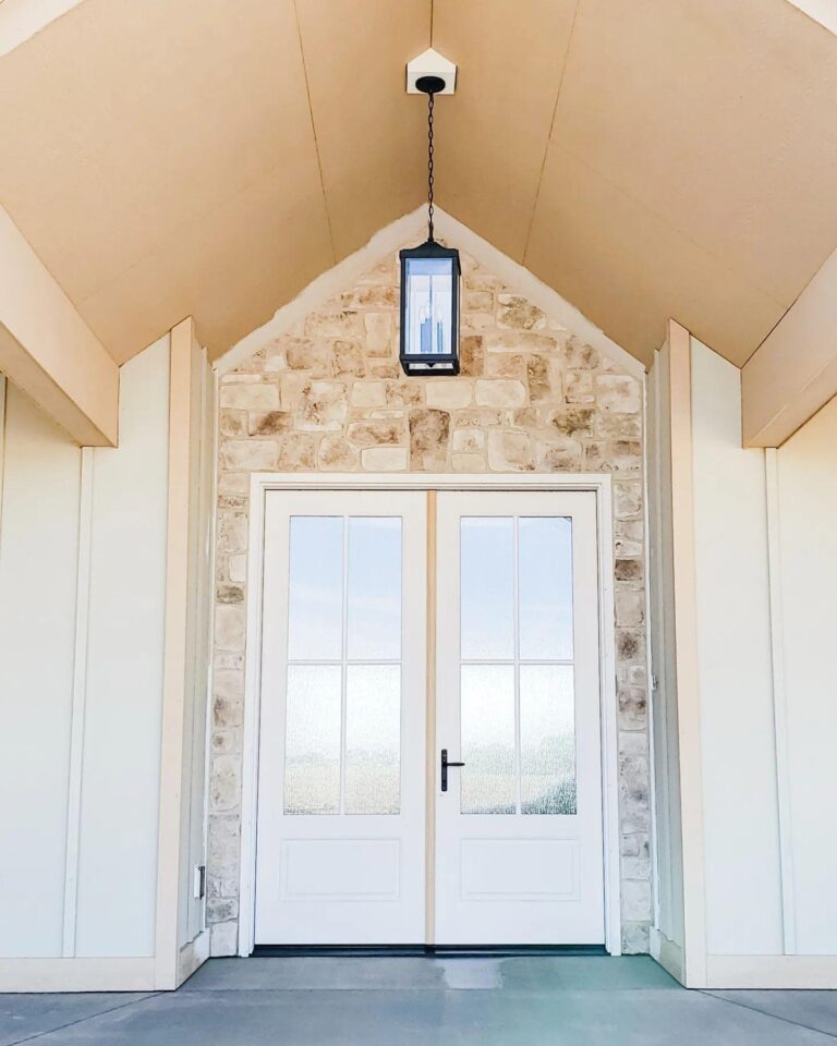 Double entry doors with glass panels and stone accents, featuring a hanging lantern, set in a modern architectural entryway.