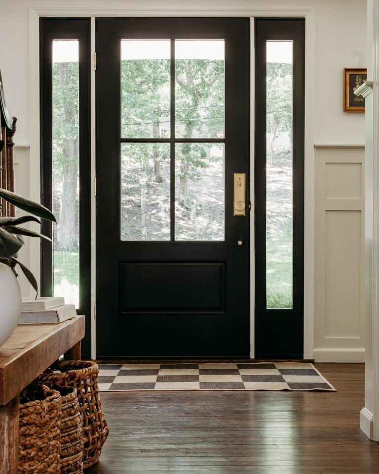 Black entry door with glass panels, surrounded by a welcoming interior featuring a checkered mat and wooden decor, showcasing Windowcrafters' exterior door offerings.