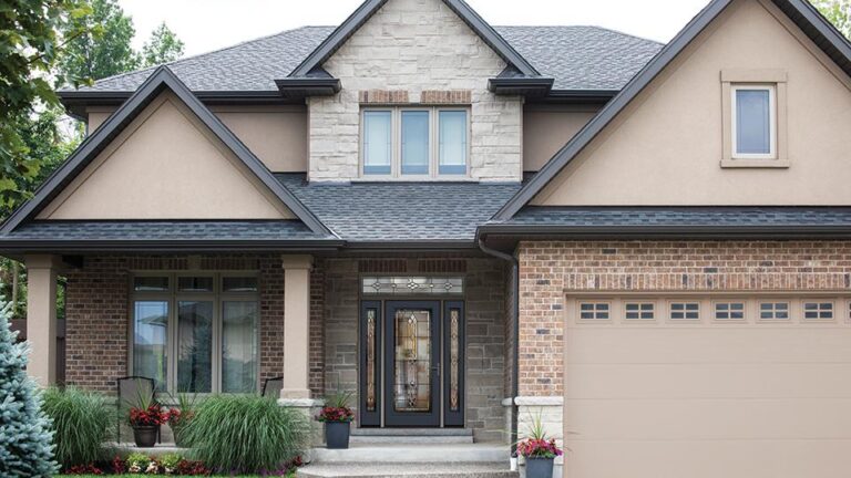 Modern home exterior with specialty vinyl windows, elegant entry door, and landscaped front yard, showcasing quality craftsmanship and design by Windowcrafters.