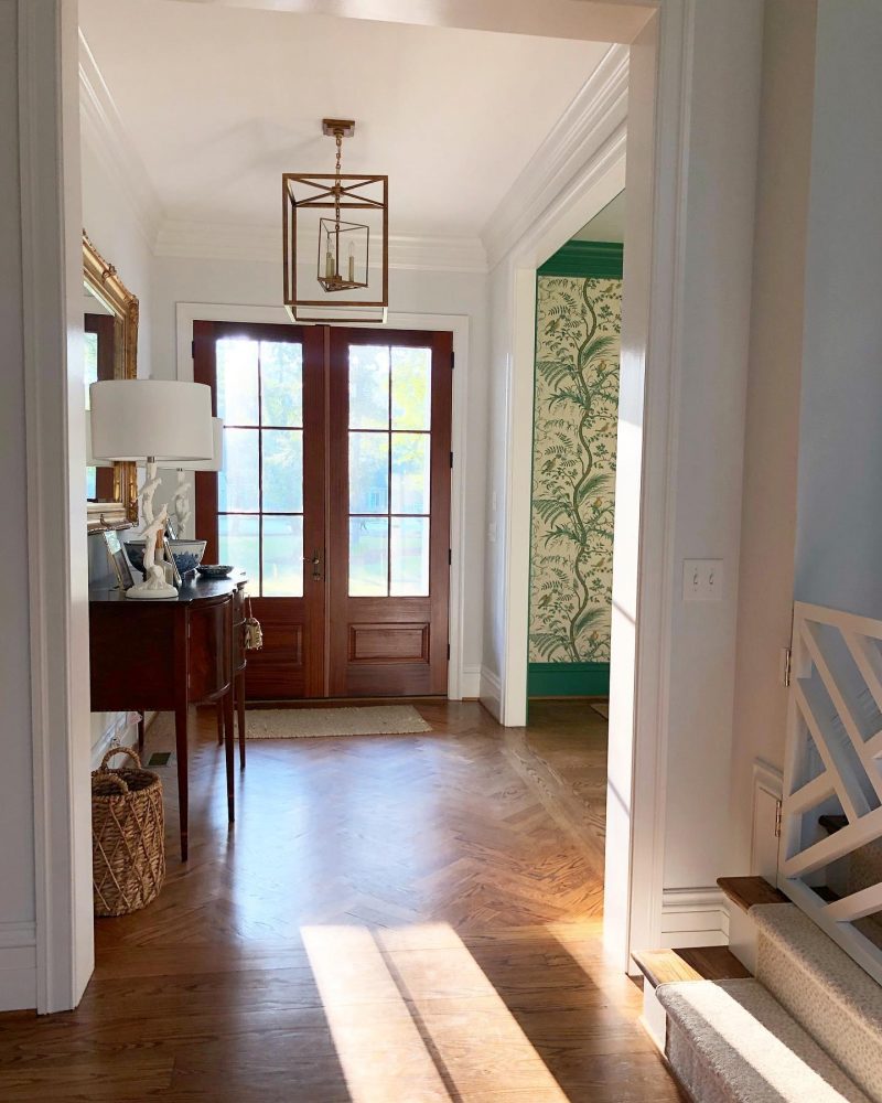 Bright entryway featuring double exterior doors, hardwood flooring, elegant light fixture, and decorative wall accents, showcasing a welcoming atmosphere for homeowners considering premium entry options.