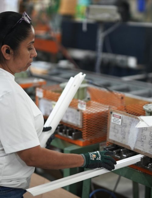 Woman working in a manufacturing facility, assembling window frames with precision, highlighting local craftsmanship and quick turnaround for custom window solutions.