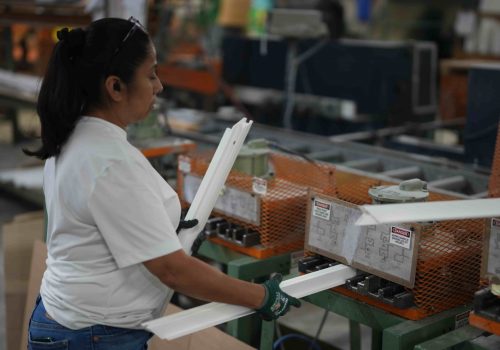 Woman in a factory setting handling vinyl window components, demonstrating local manufacturing processes for custom and stock windows at Windowcrafters.