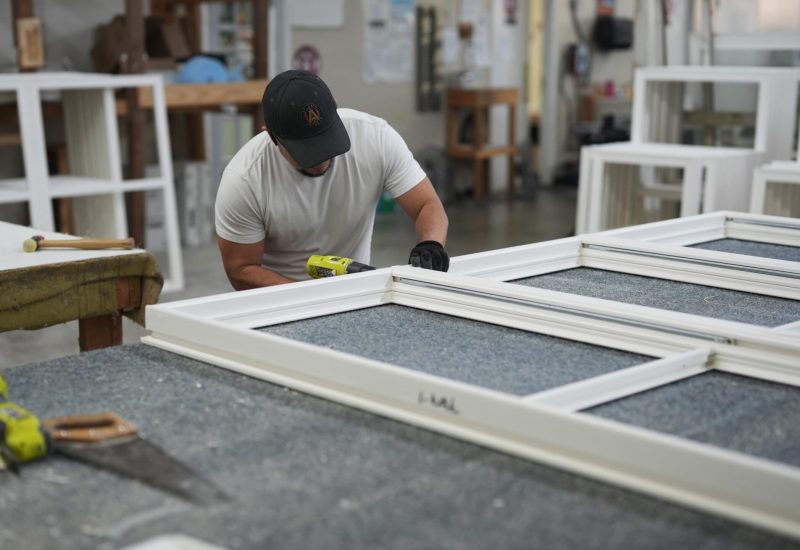 Worker assembling vinyl window frames in a workshop, demonstrating craftsmanship and attention to detail, reflecting Windowcrafters' commitment to quality and local manufacturing.