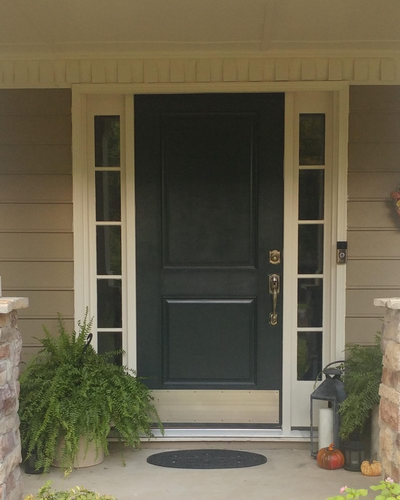 Fiberglass entry door with side lights, surrounded by greenery and decorative elements, showcasing premium exterior door options by Windowcrafters.
